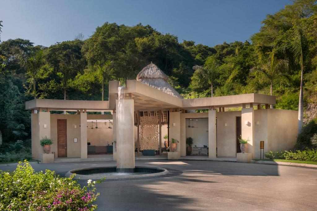 Spa treatment pavilion with thatched roof surrounded by lush tropical vegetation.