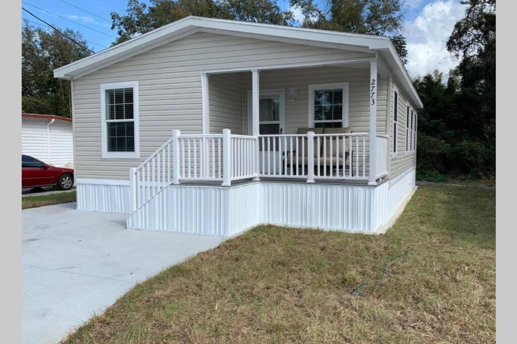 a small house with a white porch and a driveway at Resort Cottage near parks at Great Price! in Kissimmee