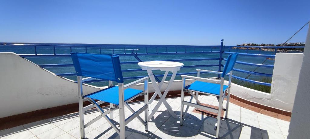 Duas cadeiras azuis e uma mesa na varanda em Splash Apartments em Makry Gialos