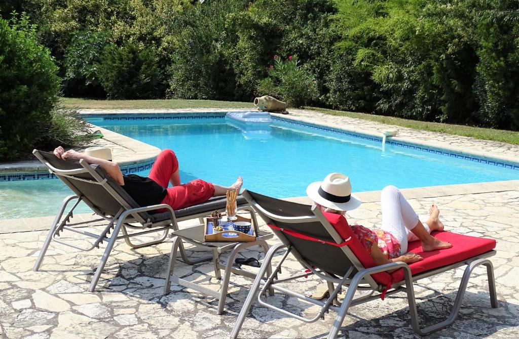 2 personnes sur des chaises longues près d'une piscine dans l'établissement Gîte et maison de vacances Campagne Valérie, à Aix-en-Provence