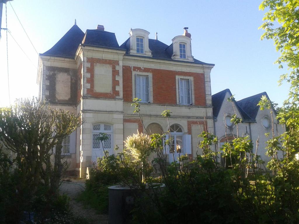 un grand bâtiment en briques avec un toit dans l'établissement COTTAGE SAINTE GENEVIEVE, à Champigny-sur-Veude