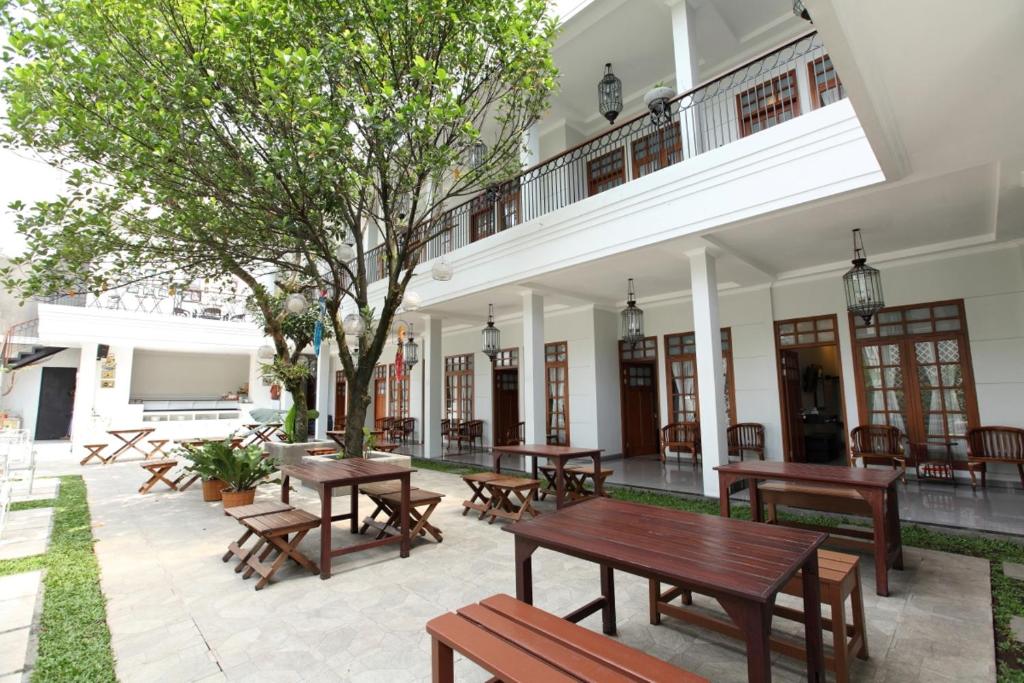 a patio with wooden tables and benches in front of a building at de' Halimun Guest House in Bandung