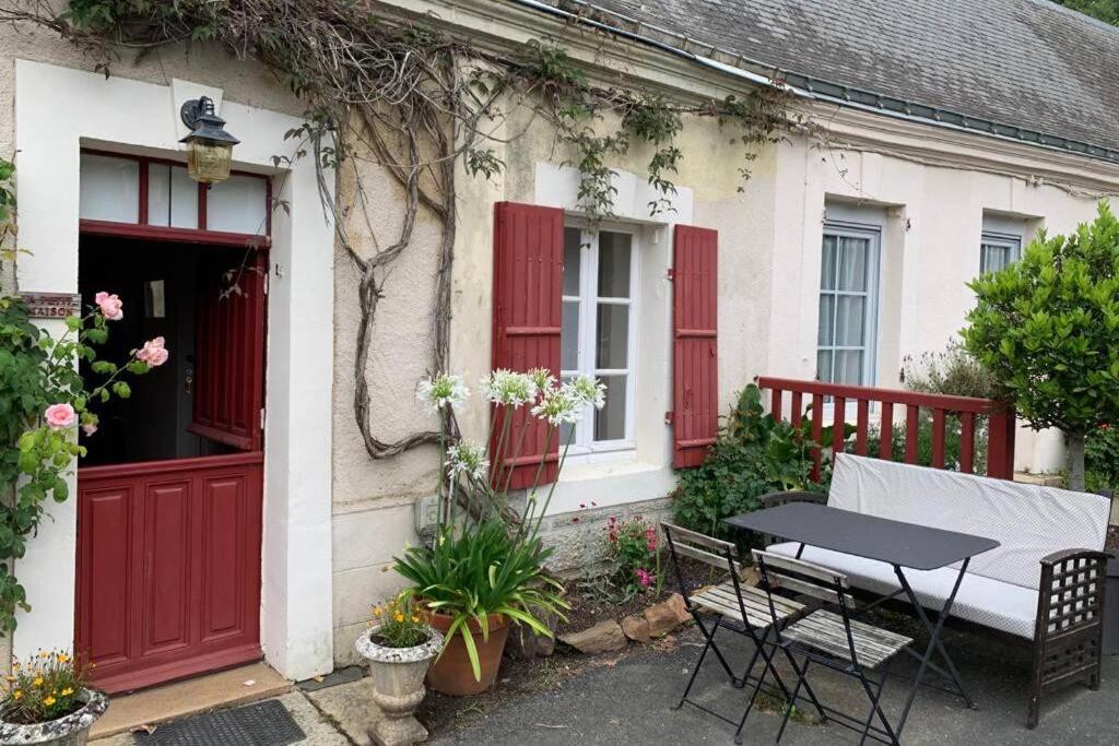 a house with red doors and a table in front of it at LA PETITE MAISON de Chenillé Changé in Chenillé-Changé