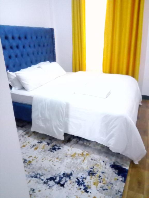 a bedroom with a bed with a blue headboard at Jacky's Fully Furnished apartments in Nakuru