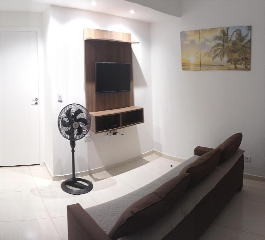 Una sala de estar con un sofá y un televisor de pantalla plana. en Temporada de frente para o mar, en Caraguatatuba