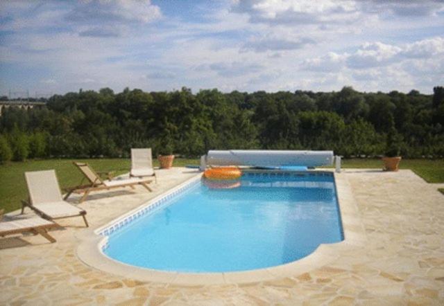 a large swimming pool with two chairs at Ferme De La Canardière in Chantilly