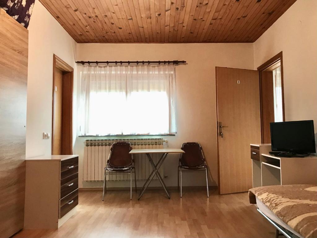 een kamer met een tafel, 2 stoelen en een raam bij Sobe Markočević in Teslić