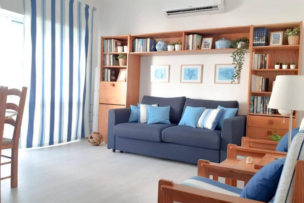 een woonkamer met een blauwe bank en boekenplanken bij Cozy beach front apartment in Portimão