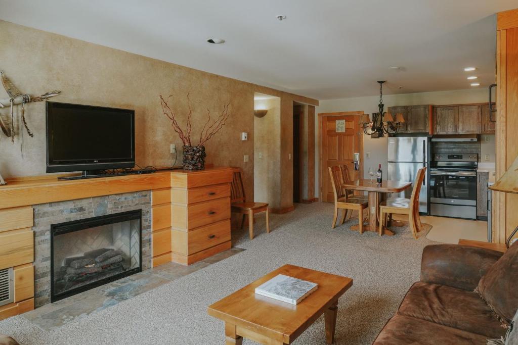 ein Wohnzimmer mit einem Kamin und einem TV in der Unterkunft Shoshone Condos at Big Sky Resort in Big Sky