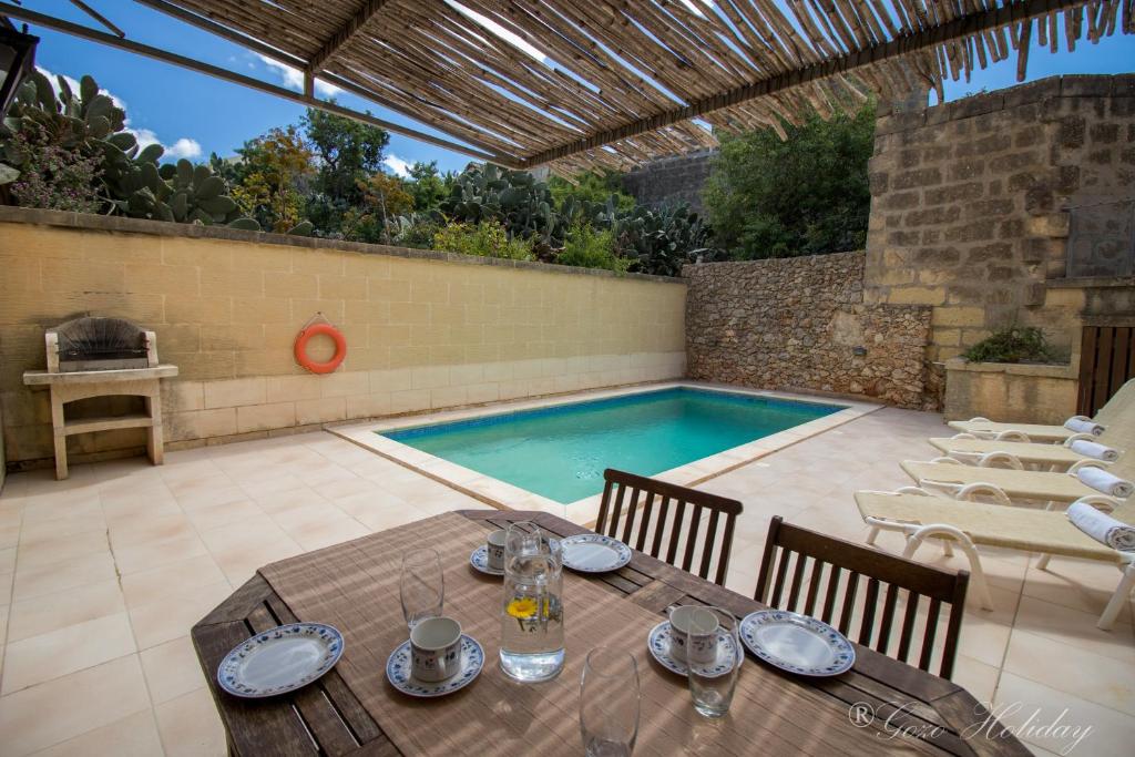 eine Terrasse mit einem Tisch und einem Pool in der Unterkunft Ta Guzeppi Xaghra in Xagħra