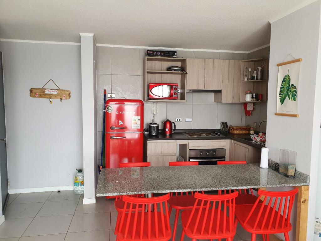 cocina con sillas rojas y nevera roja en Descanso frente al mar, en Los Molles