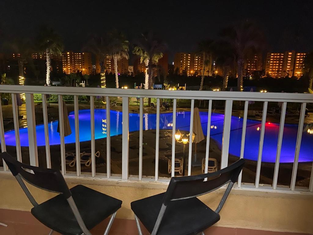 a couple of chairs sitting on a balcony at night at Pool View Apartment in Golf Porto Marina in El Alamein