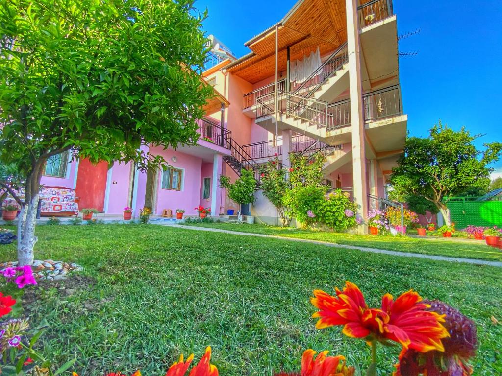 Un bâtiment rose avec des fleurs dans la cour dans l'établissement Vila Deda Tale, à Lezhë