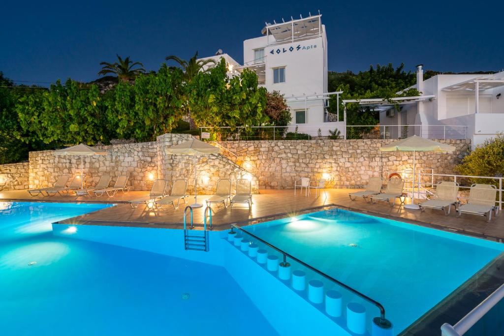 a pool at night with a villa in the background at Eolos Apartments in Chania Town