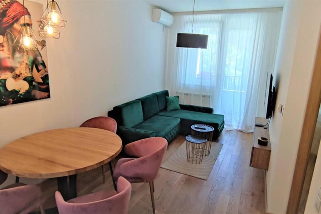 uma sala de estar com um sofá verde e uma mesa e cadeiras em SNP city center lux em Novi Sad