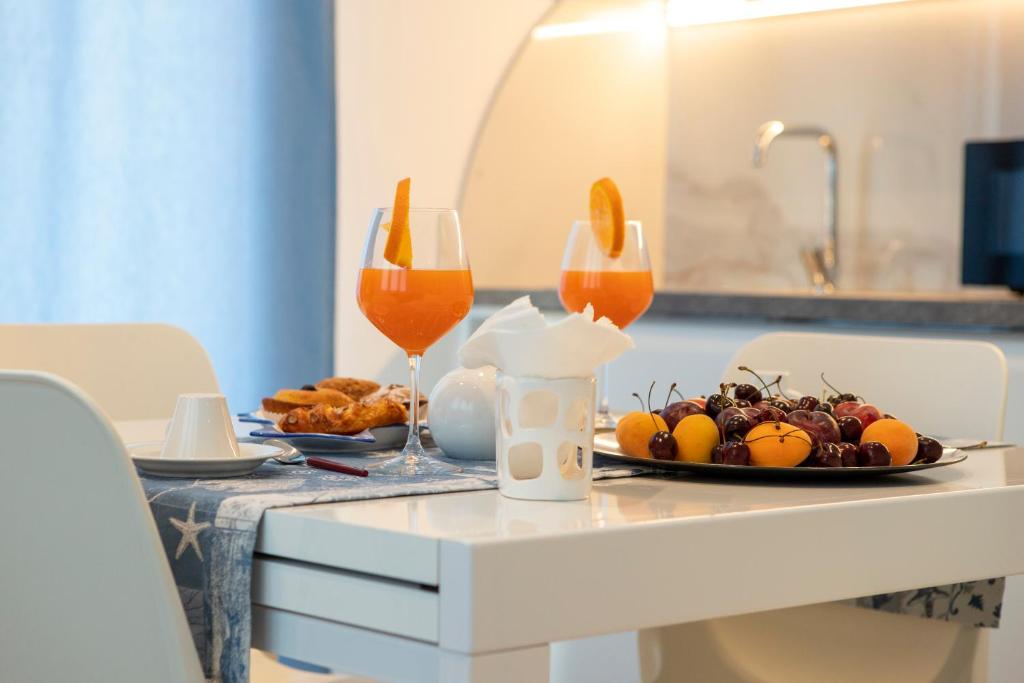 une table avec une assiette de fruits et deux verres à vin dans l'établissement Virgilio hosting Casa Nuovissima Vista Mare, à Torre Pali