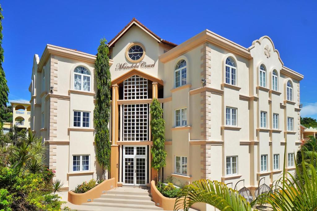 a large building with trees in front of it at Mandela Court Suites Grenada in Lance aux Épines