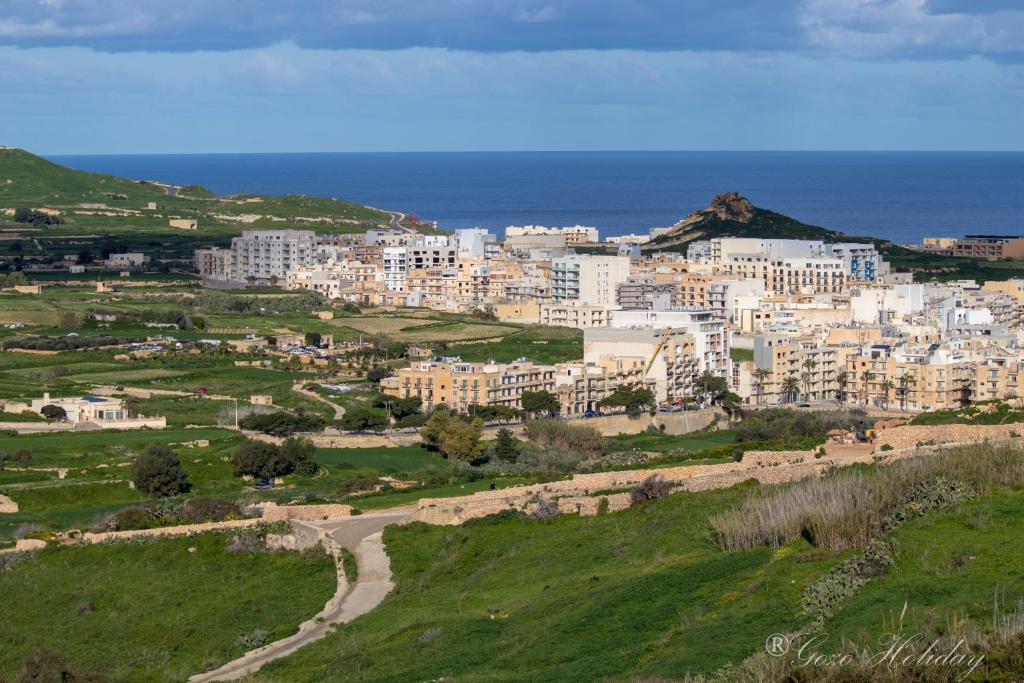 a group of buildings on a hill next to the ocean at Orchidea Xaghra in Il-Pergla