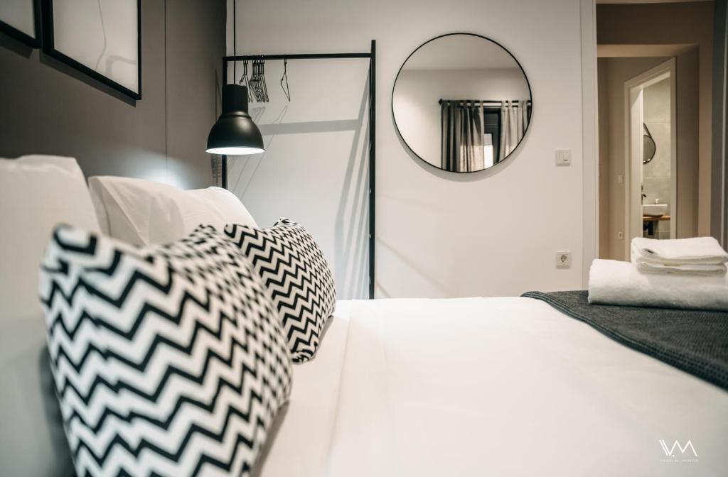 - une chambre avec un lit blanc et un miroir dans l'établissement FSM APARTMENTS PERDIKA, à Perdika
