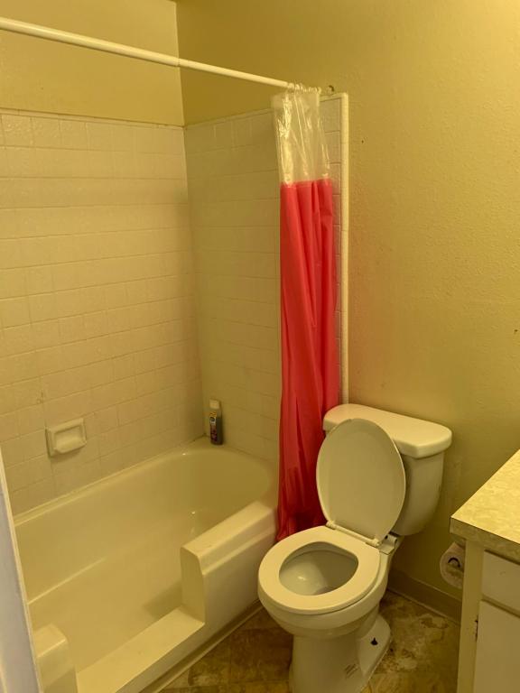 La salle de bains est pourvue de toilettes et d'une baignoire avec rideau de douche rouge. dans l'établissement LA/Beverly Hills Hotel Style Suite (C19), à Los Angeles