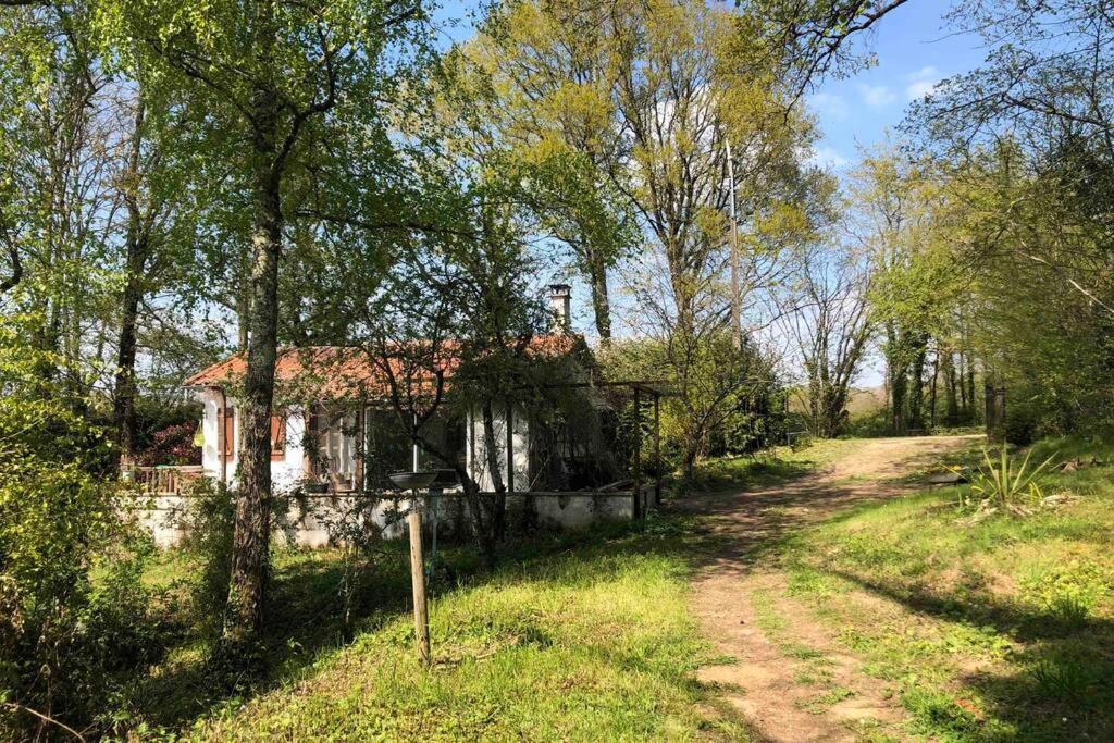 une vieille maison dans un champ à côté d'un chemin de terre dans l'établissement La Petite Maison au bord de l’étang, à Chirac