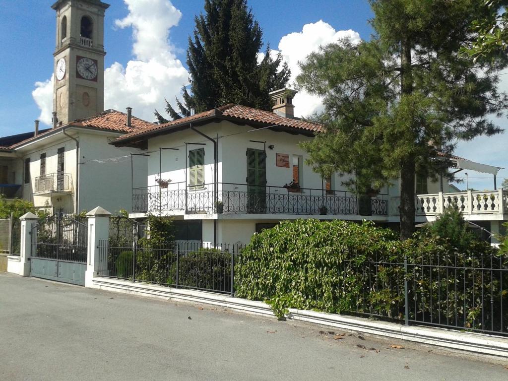 ein weißes Haus mit einem Uhrturm und einem Zaun in der Unterkunft Il Forno Dal 1922 in Bene Vagienna