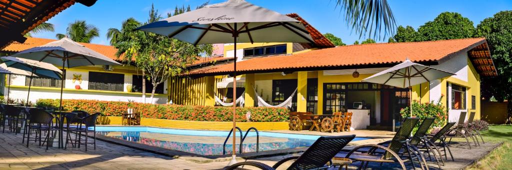 um resort com uma piscina e cadeiras e um guarda-sol em Sunshine Cumbuco em Cumbuco