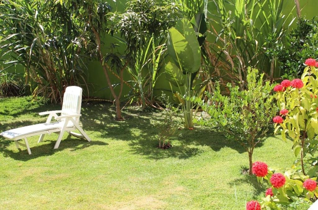 une chaise blanche assise dans l'herbe dans un jardin dans l'établissement RECANTO JK, à Taguatinga