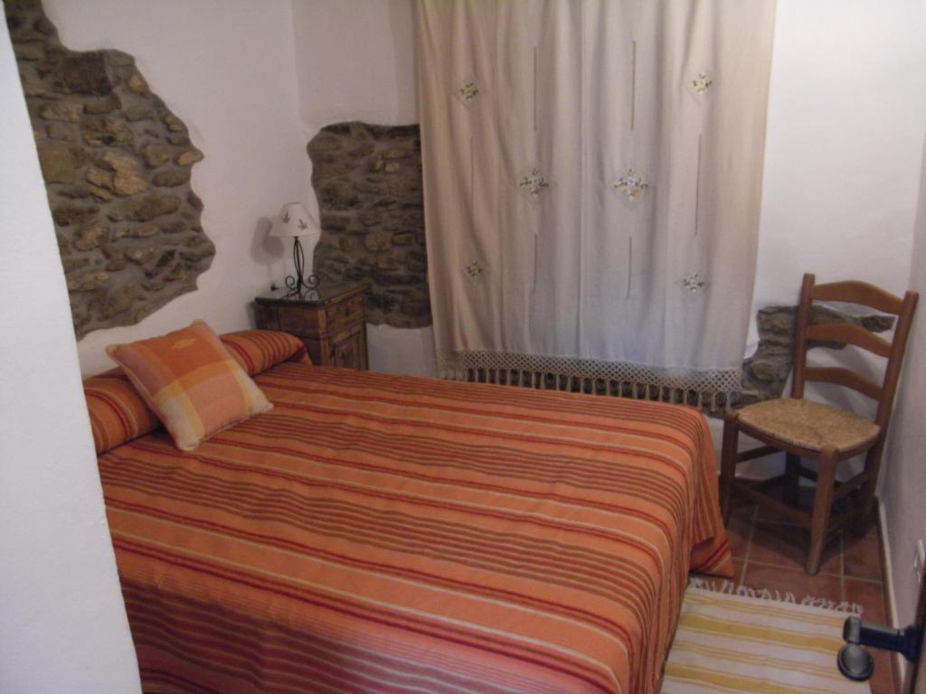 a bedroom with a bed and a chair in a room at La Casilla del Pastor in Vélez-Málaga