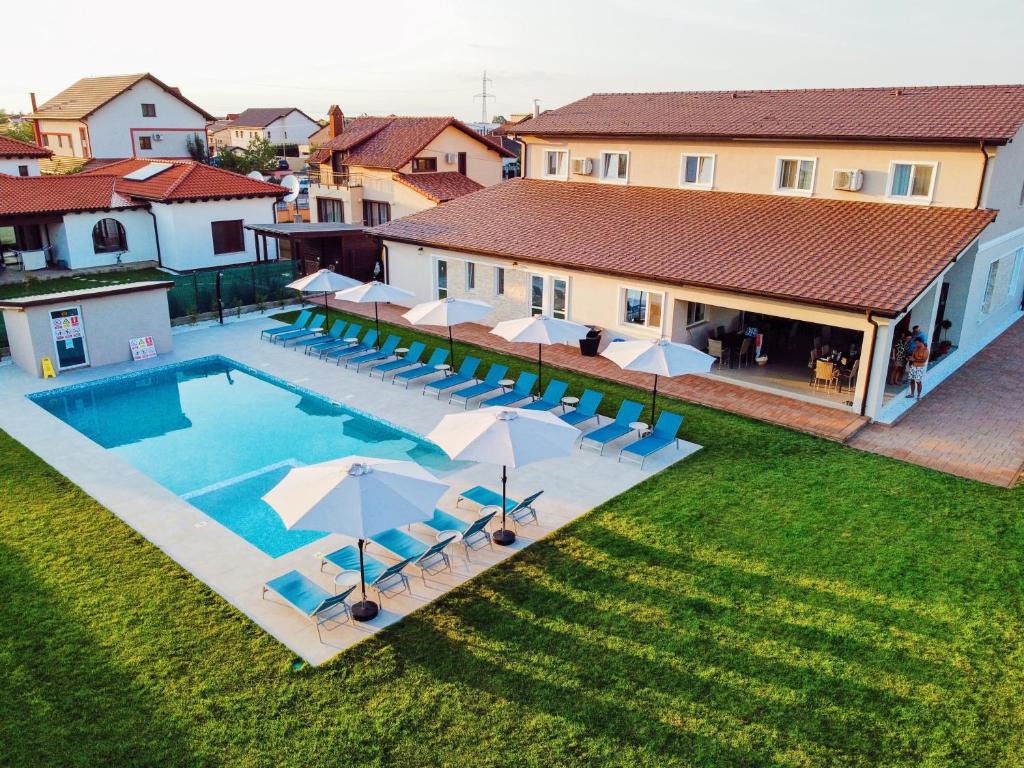 Dumbrăviţa的住宿－Pensiunea Agroturistica Marco，享有带椅子和遮阳伞的游泳池的上方景色