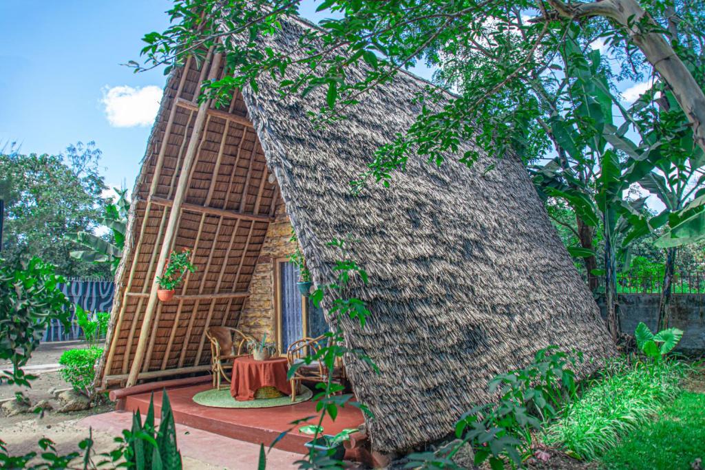 Charming Eco-Homestay near Kilimanjaro International Airport في أروشا: منزل صغير مع جذع شجرة كبير