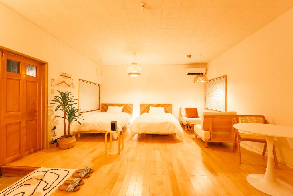 1 Schlafzimmer mit 2 Betten, einem Tisch und Stühlen in der Unterkunft Sunnyside in Miyako-jima