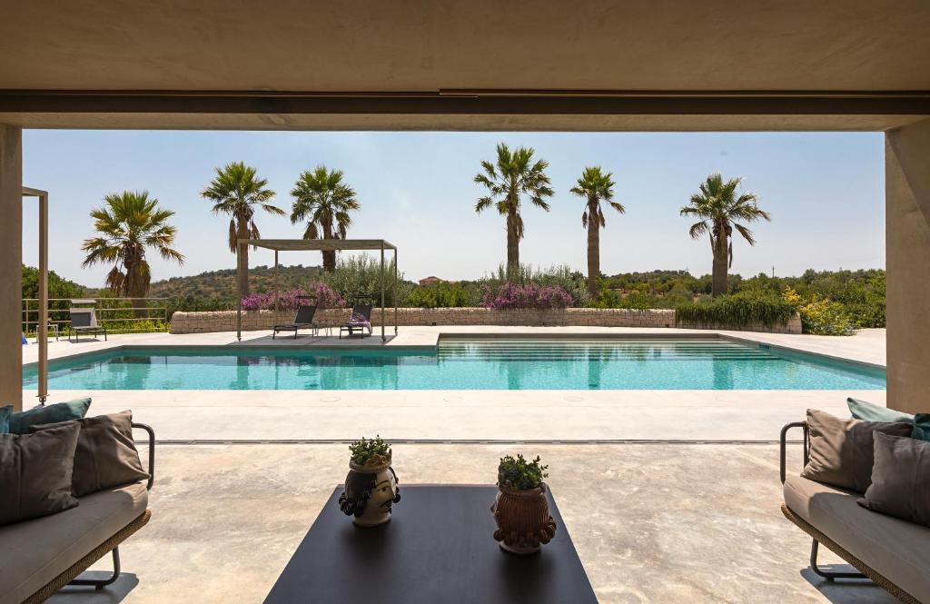 a swimming pool with palm trees in the background at Country House Villadorata in Noto