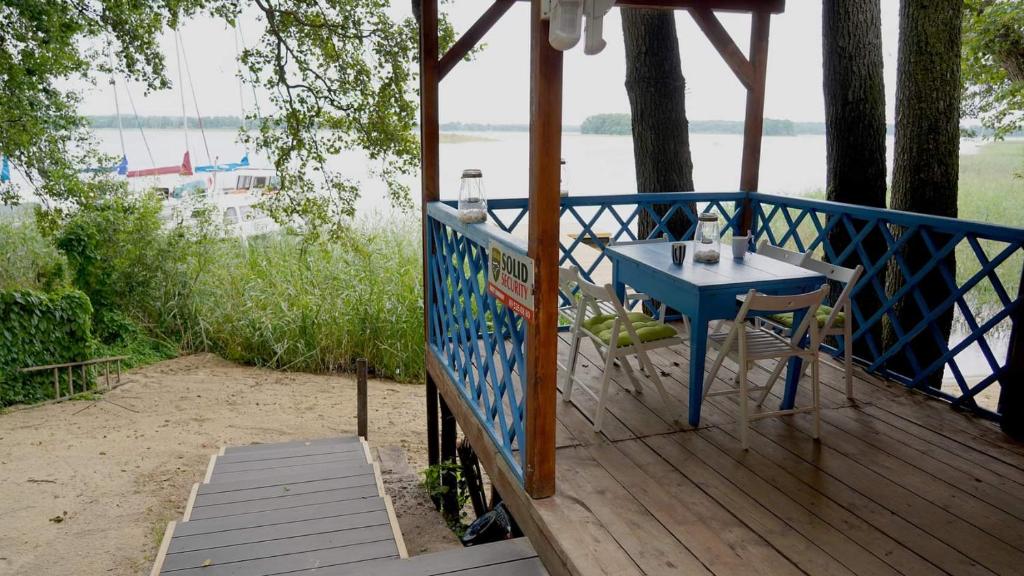 einen blauen Tisch und Stühle auf einer Terrasse mit Blick auf das Wasser in der Unterkunft Luksusowy dom z linią brzegową Jezioraka. in Siemiany