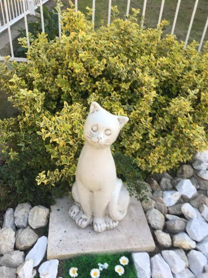 a white cat statue sitting in front of a bush at Lavender in Hévíz