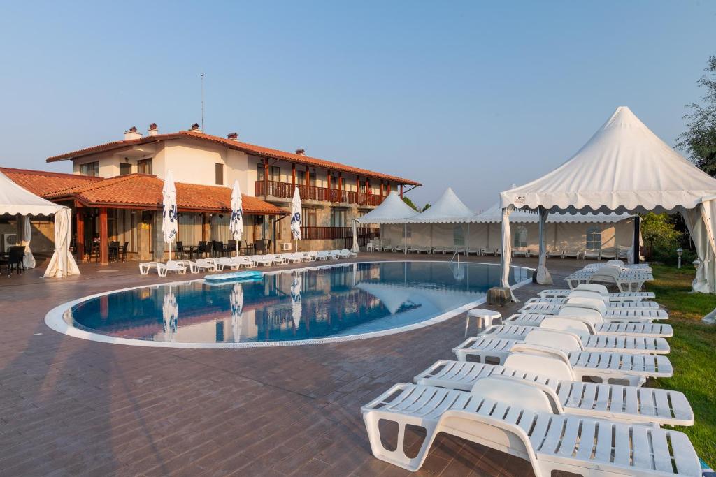 - une rangée de chaises longues blanches à côté de la piscine dans l'établissement Villa Trakia, à Simeonovo