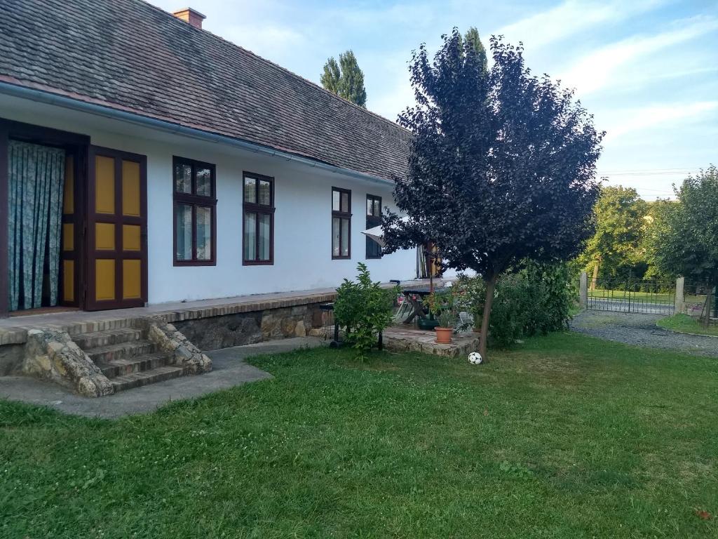 ein weißes Haus mit einem Baum im Hof in der Unterkunft Akác Ház in Feked