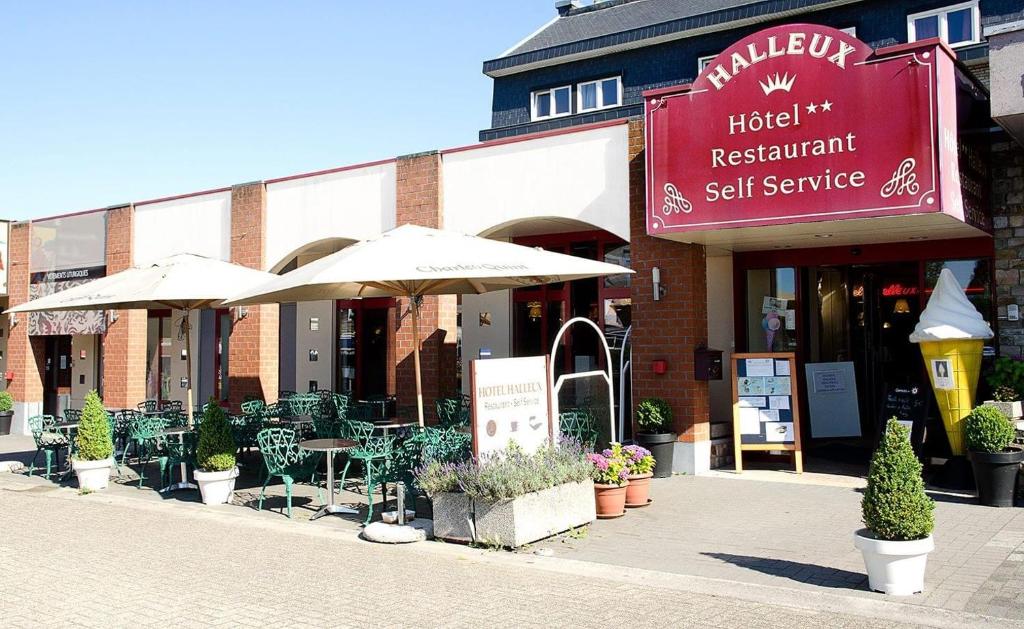 um restaurante com mesas e guarda-sóis em frente a um edifício em Hotel Halleux em Banneux