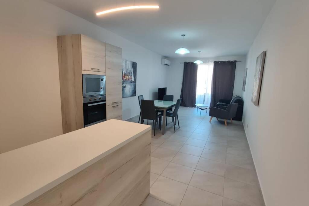 a kitchen and living room with a table and chairs at Brand new 3 bedroom Apartment close to the sea in Il-Gżira