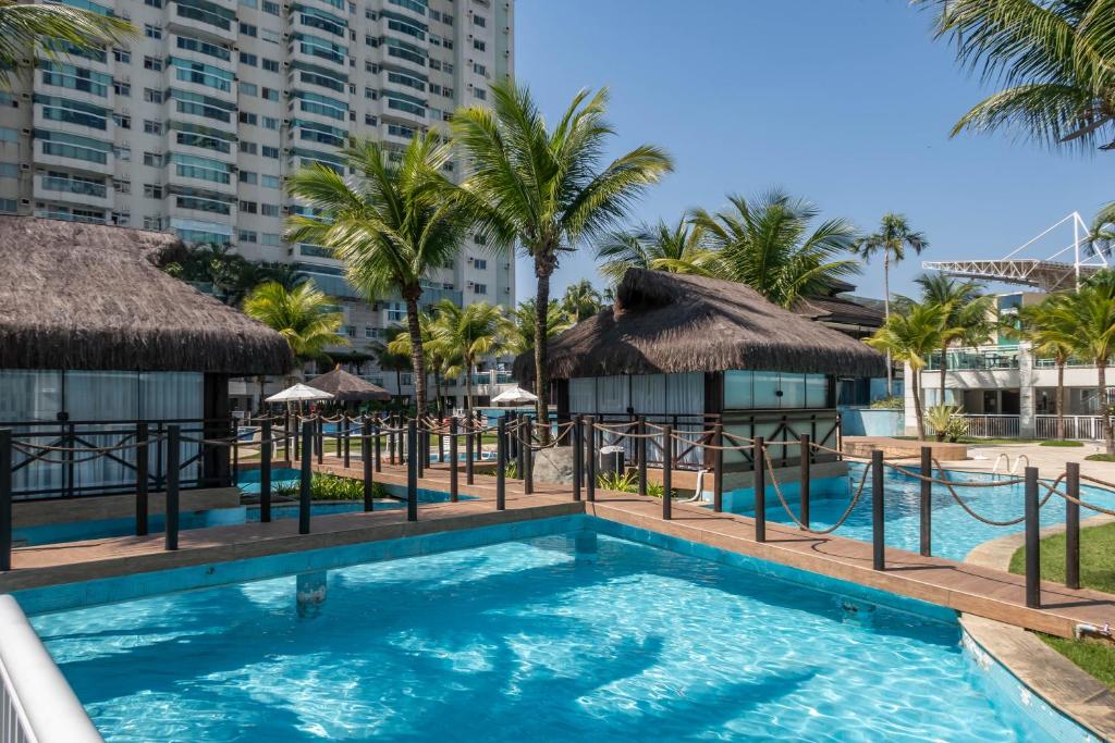 uma piscina no resort com palmeiras e edifícios em Bora Bora Resort Barra da Tijuca no Rio de Janeiro