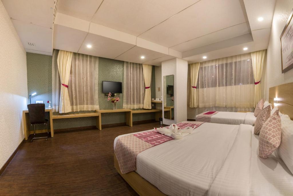a hotel room with two beds and a television at The Solitaire Express in Dehradun