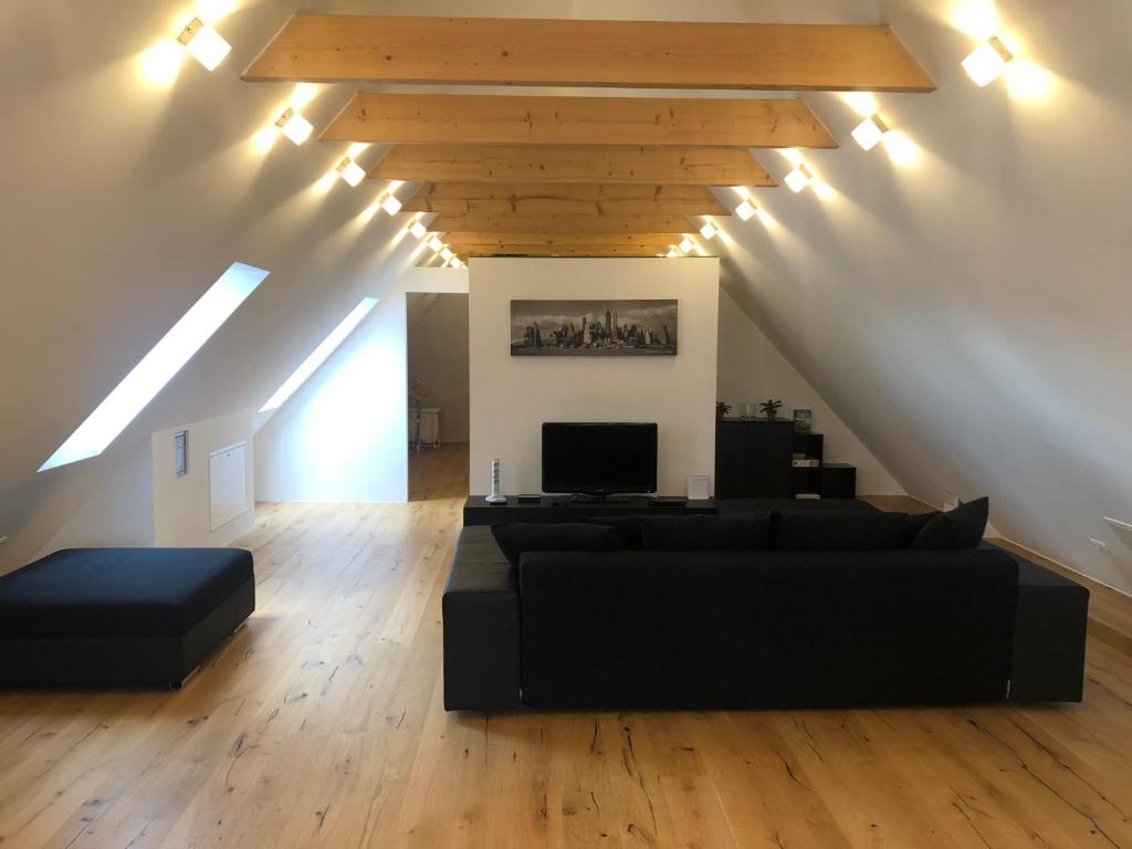 un soggiorno con divano nero e soffitti in legno di Loft Dachsberg a Krems an der Donau