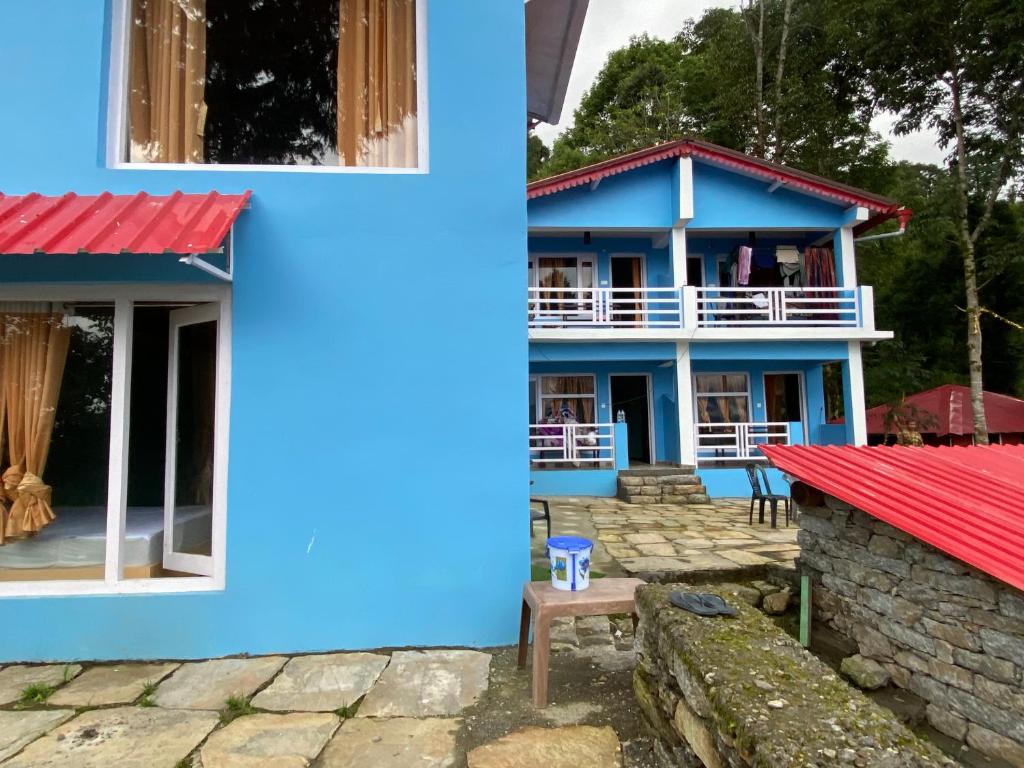 a blue house with a red roof at JAYANTI MOTHER NATURE HOMESTAY MUNSYARI in Munsyari
