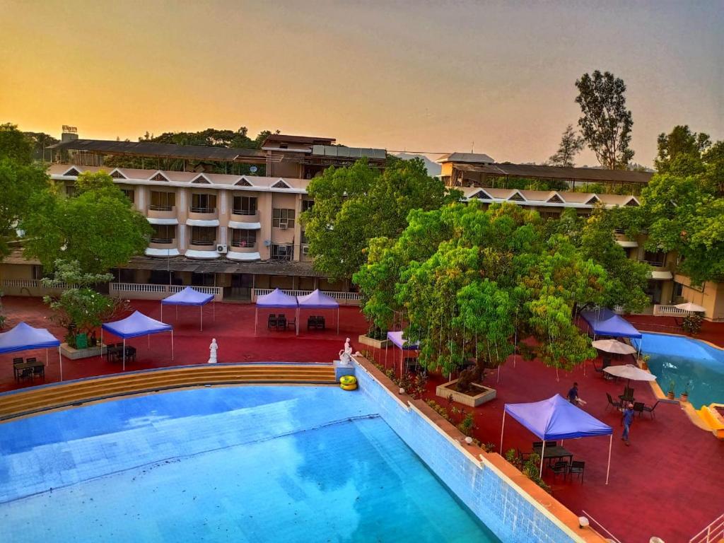 Aron Resort Lonavala - Near Old Mumbai Pune Highway في لونافالا: اطلالة علوية على مسبح في فندق