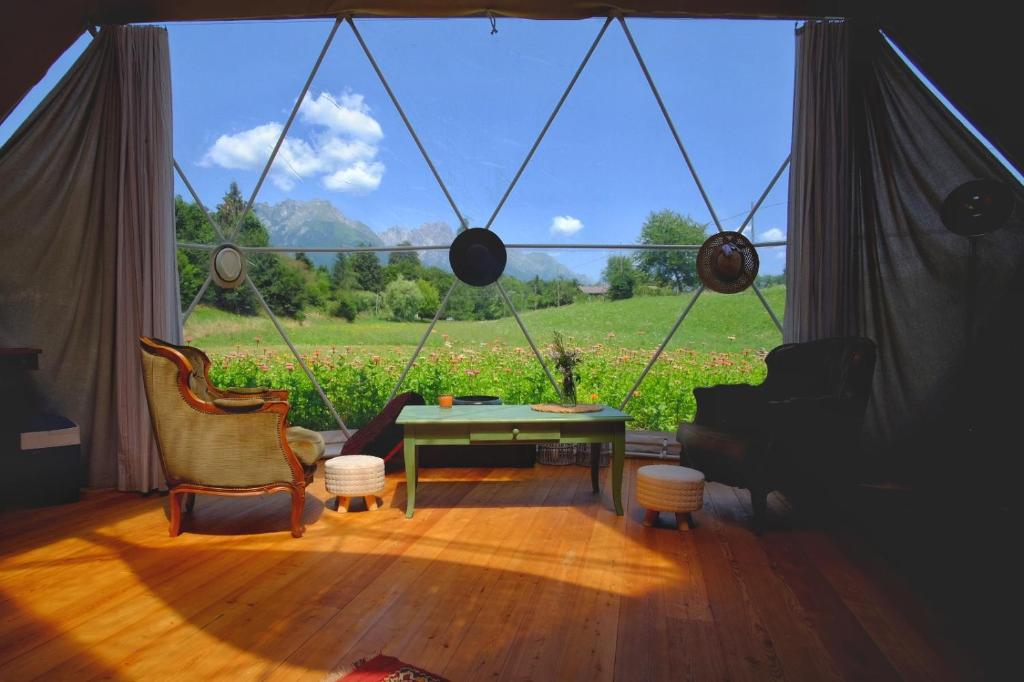una camera con una grande finestra con tavolo e sedie di That's life Glamping - Dolomite Experience a Dorgnan