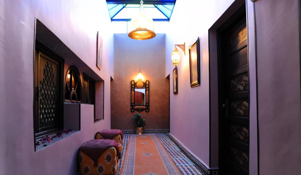 a hallway with pink walls and a hallway with chairs and a door at Collier De La Colombe in Meknès