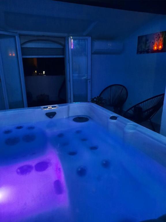 - une baignoire dans une chambre avec des lumières violettes dans l'établissement Maison avec jacuzzi, à Saint-Mitre-les-Remparts