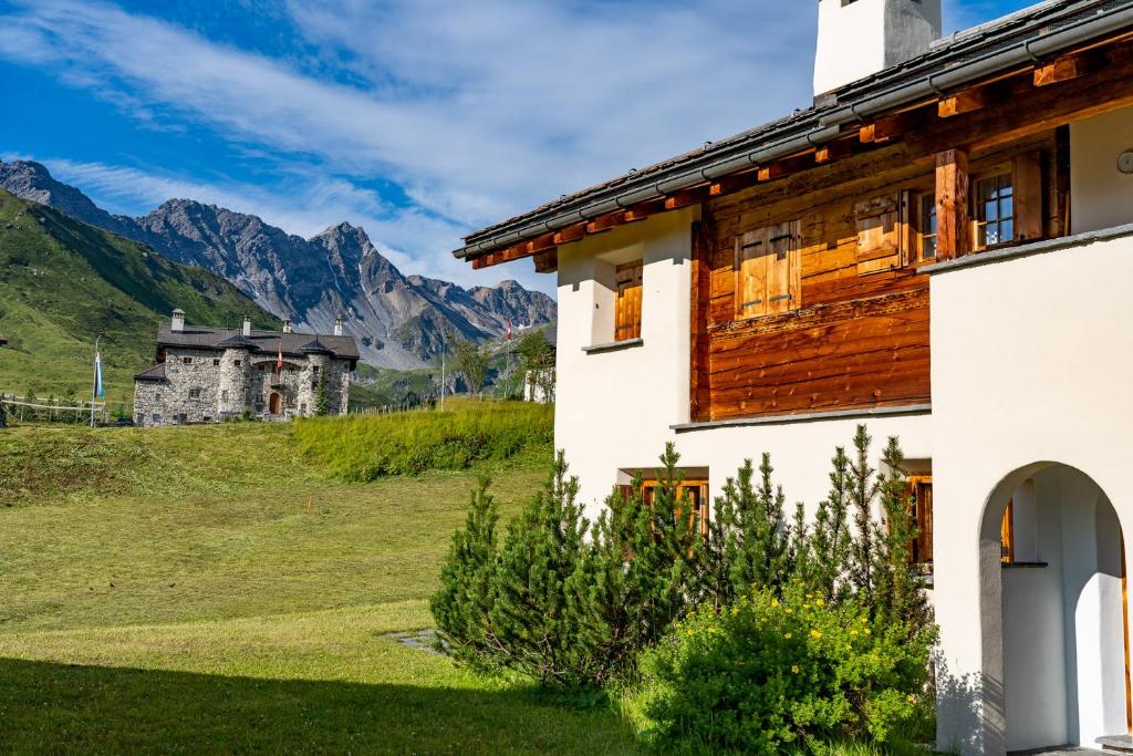 a house in a field with mountains in the background at Kulmwiesli in Arosa