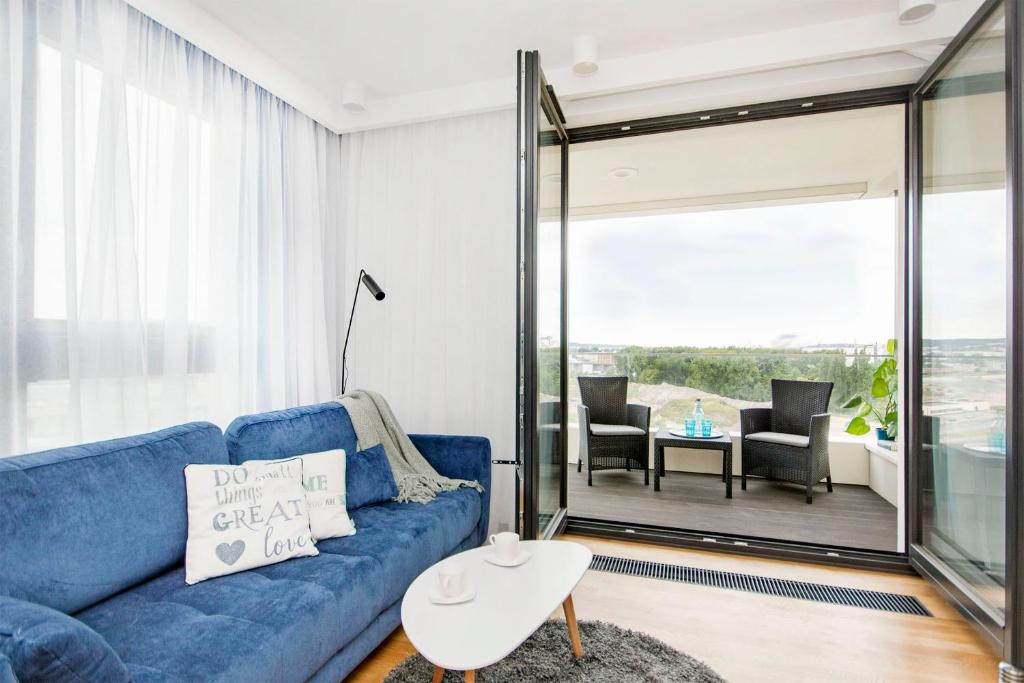 a living room with a blue couch and a balcony at Apartament Rodzinny Portova in Gdynia