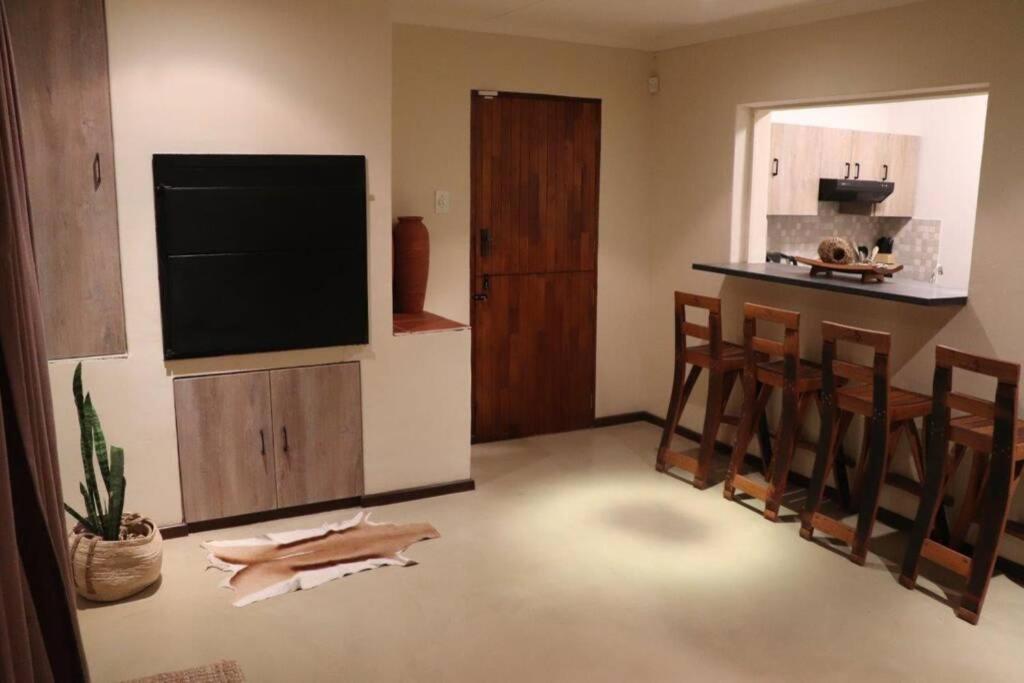 ein Wohnzimmer mit einem Flachbild-TV und eine Küche in der Unterkunft du Repos (Lovely & Relaxing 2-Bedroom Unit with Patio) in Springbok